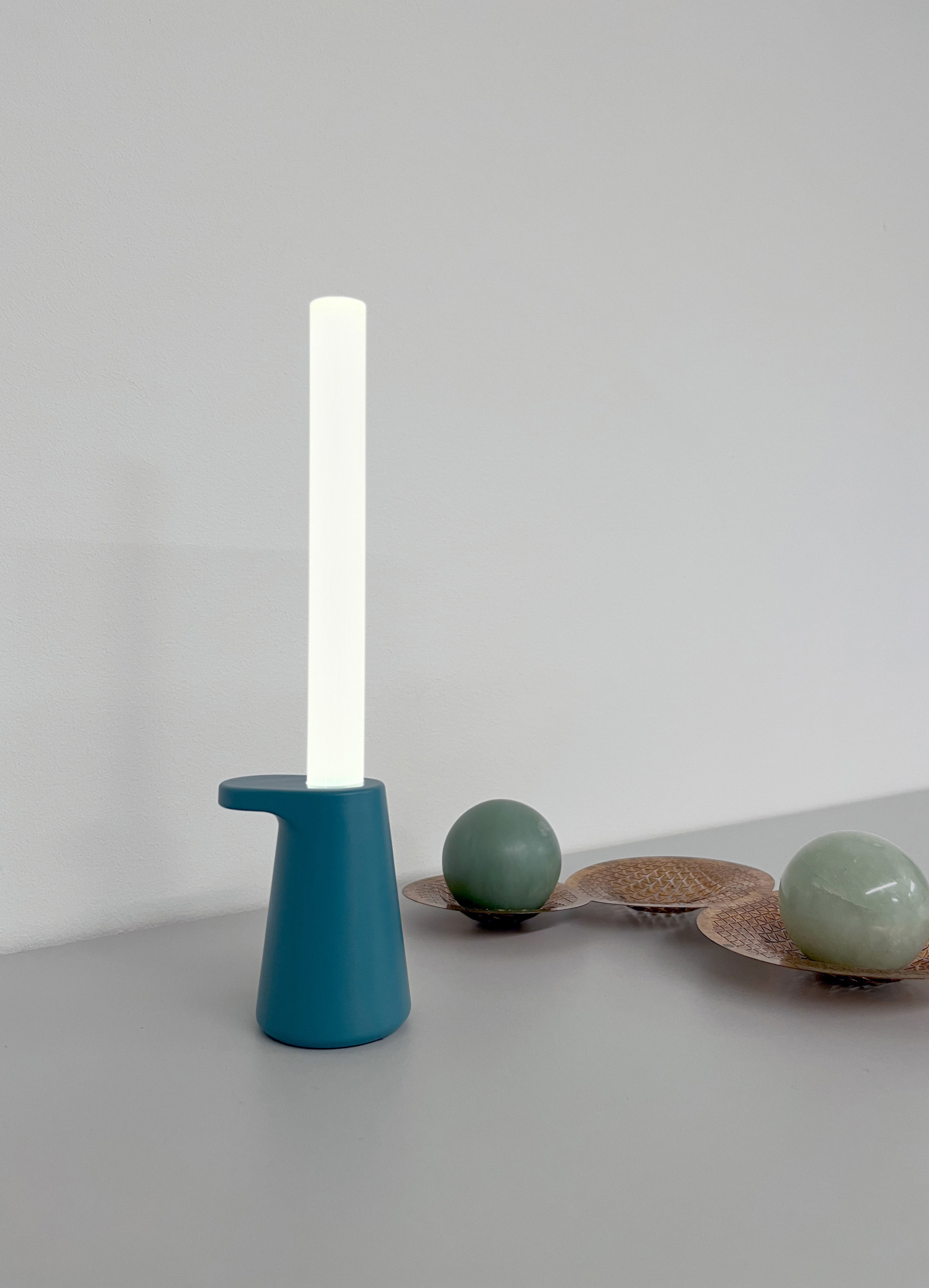 Photograph of the Candle light on a table beside other design objects.
